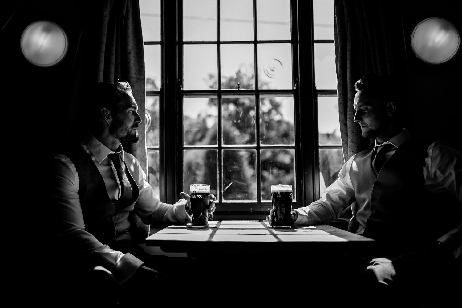 A romantic black and white photo captures shadows and window light during a couples session.
