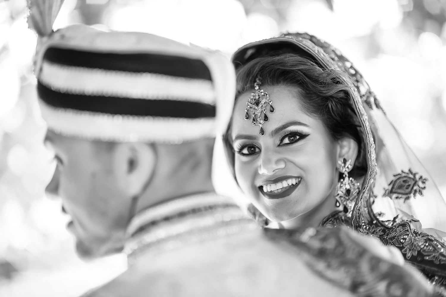 Black and white close-up portraits showing joyful moments during a traditional South Asian wedding ceremony.