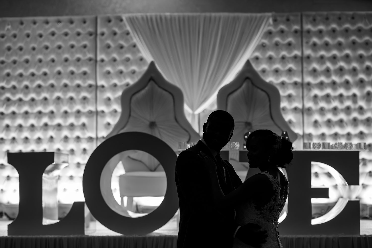 Wedding reception venue with modern geometric wall decor and white draping.