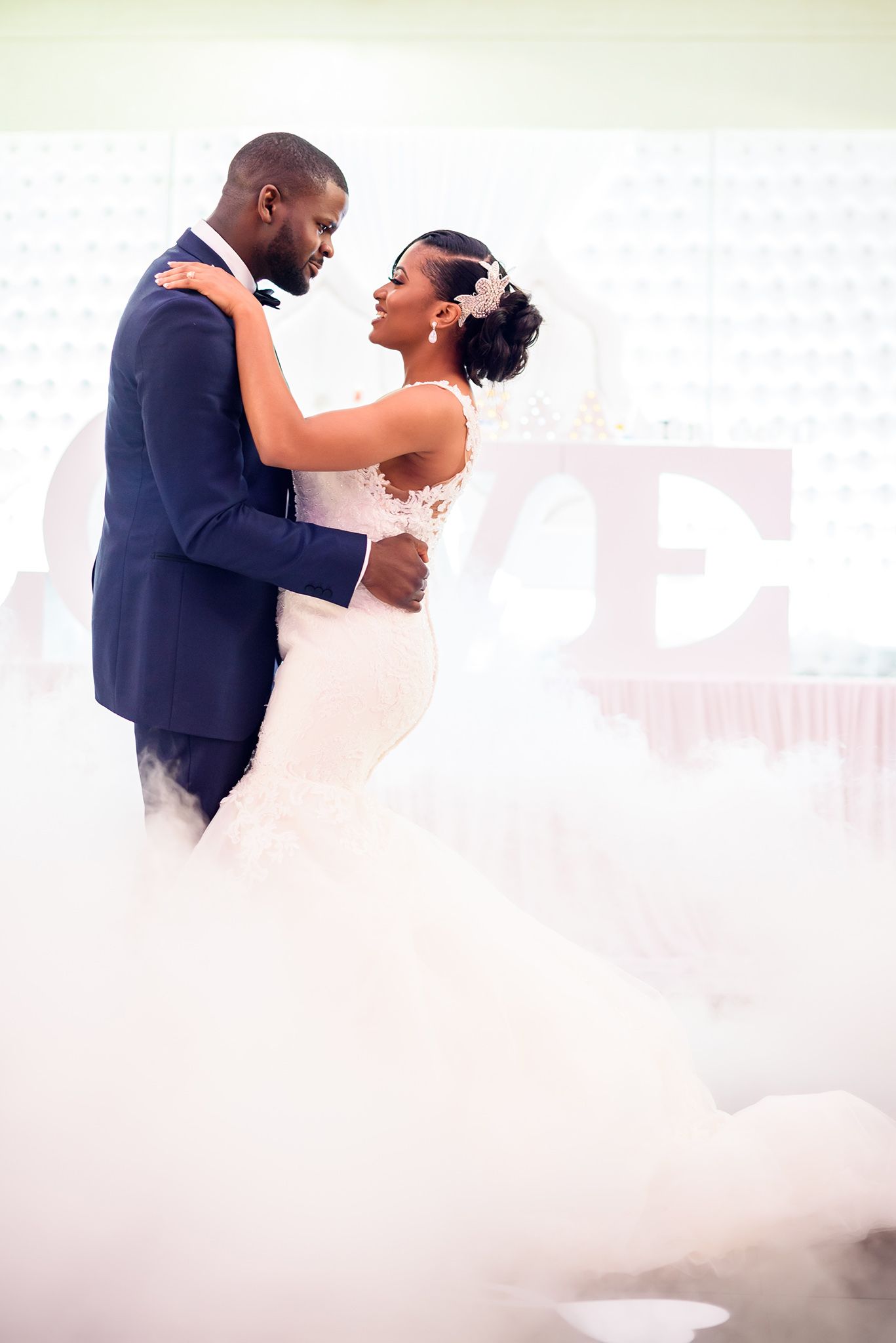 Romantic first dance of newlyweds surrounded by fog effects on the dance floor.