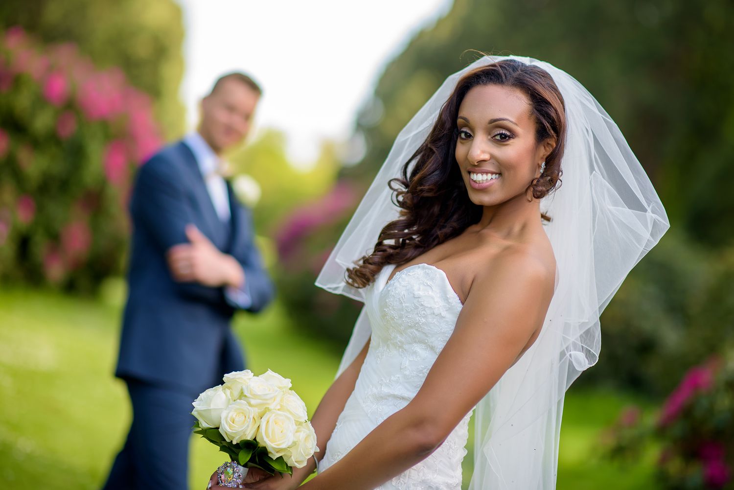 Wedding portraits captured in garden setting with vibrant pink florals.