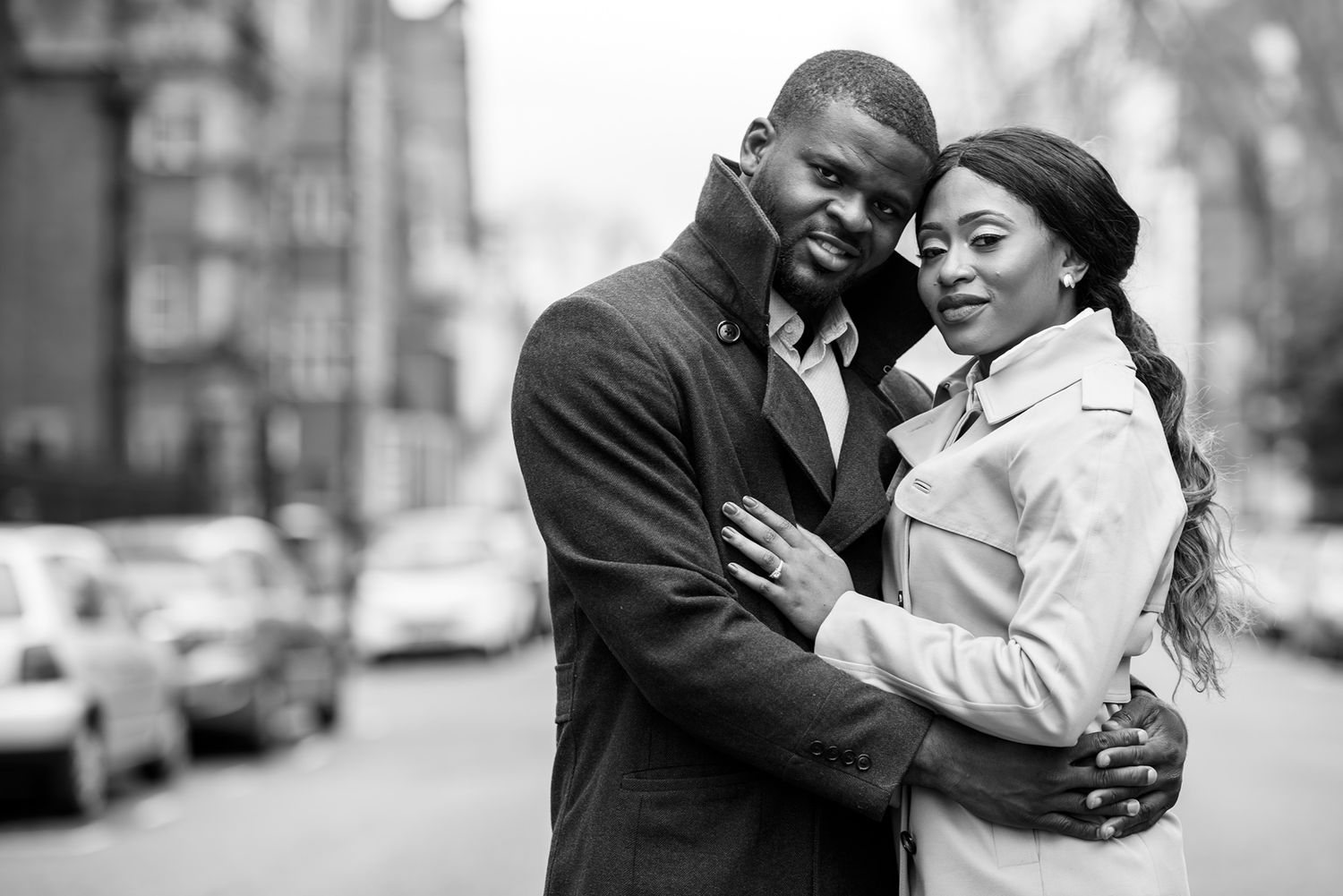 Intimate couple portrait on a city street with winter coats and natural urban backdrop.