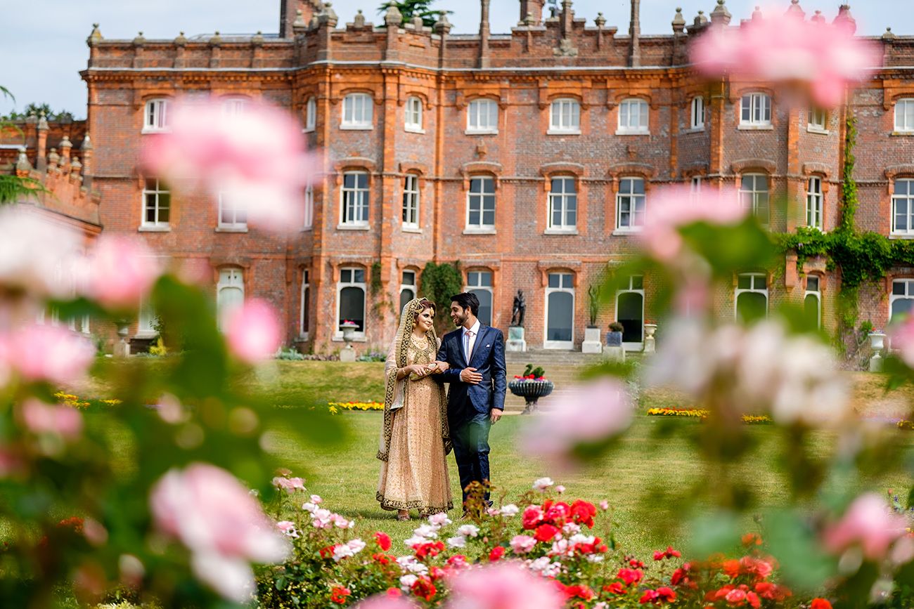 Historic brick mansion with pink flowering trees blooming in the foreground garden.