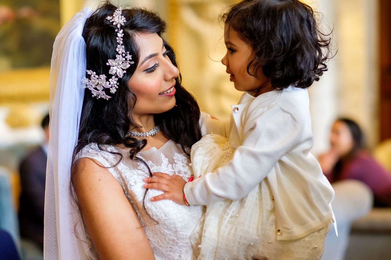 A bride in a white dress shares tender moments with a small child during a wedding celebration.
