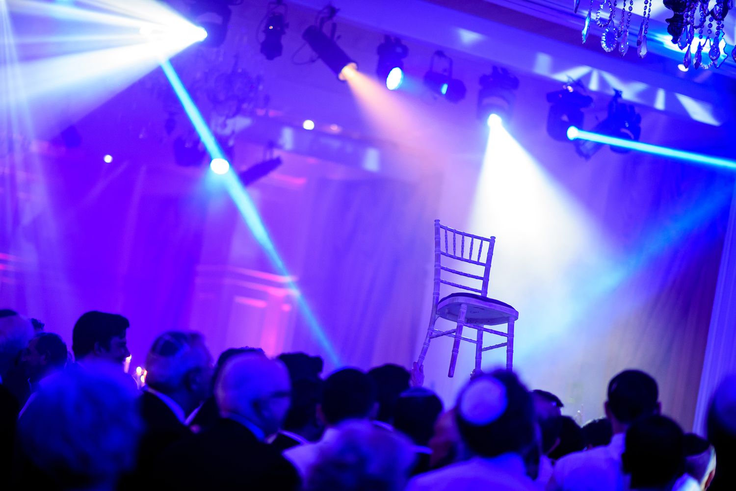 Concert venue illuminated with dramatic blue stage lighting and silhouetted crowd.
