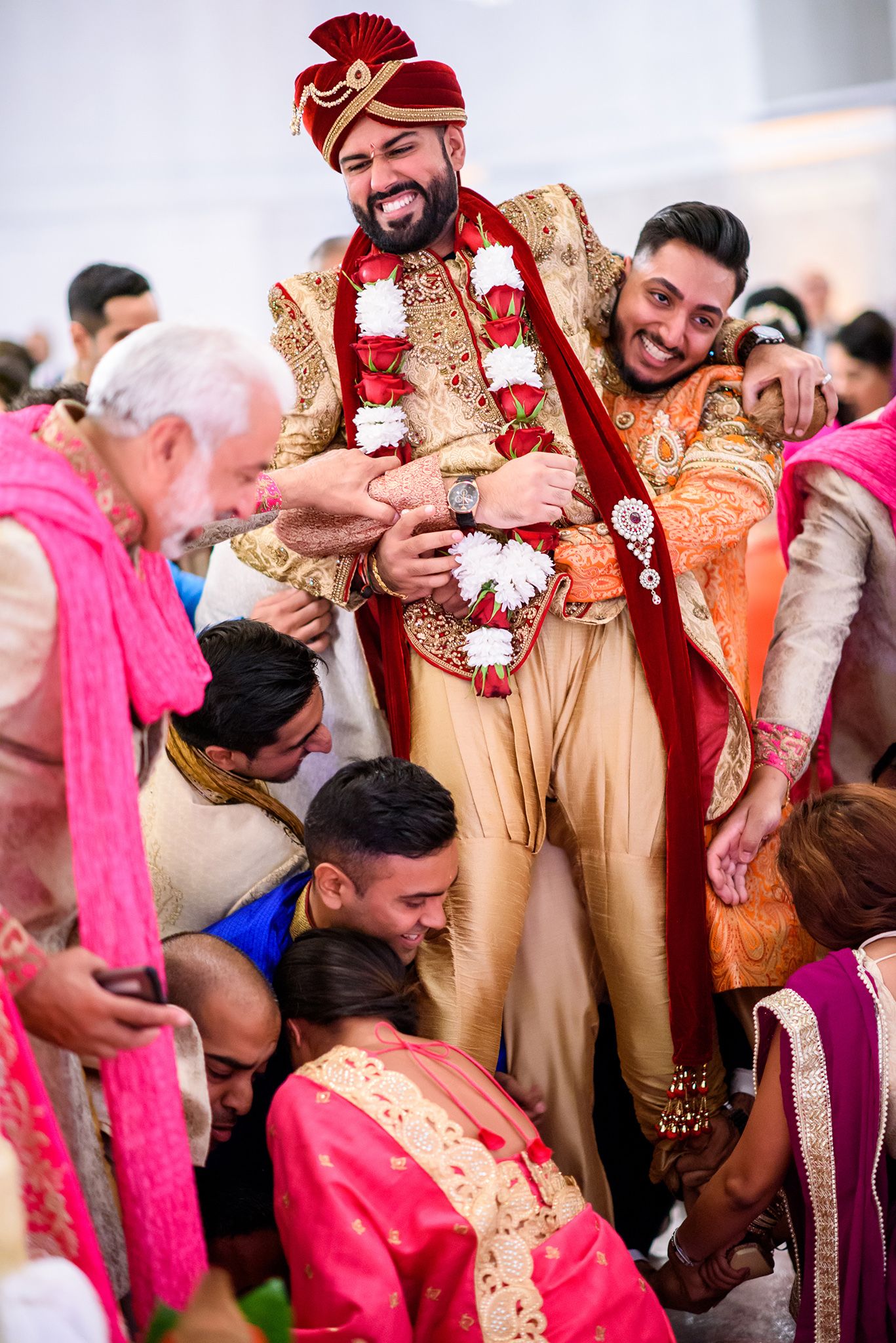 Joyous celebration at an Indian wedding with guests in traditional formal attire.