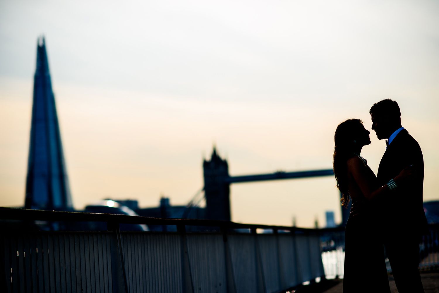 Romantic silhouette of couple near Tower Bridge at dusk in London.
