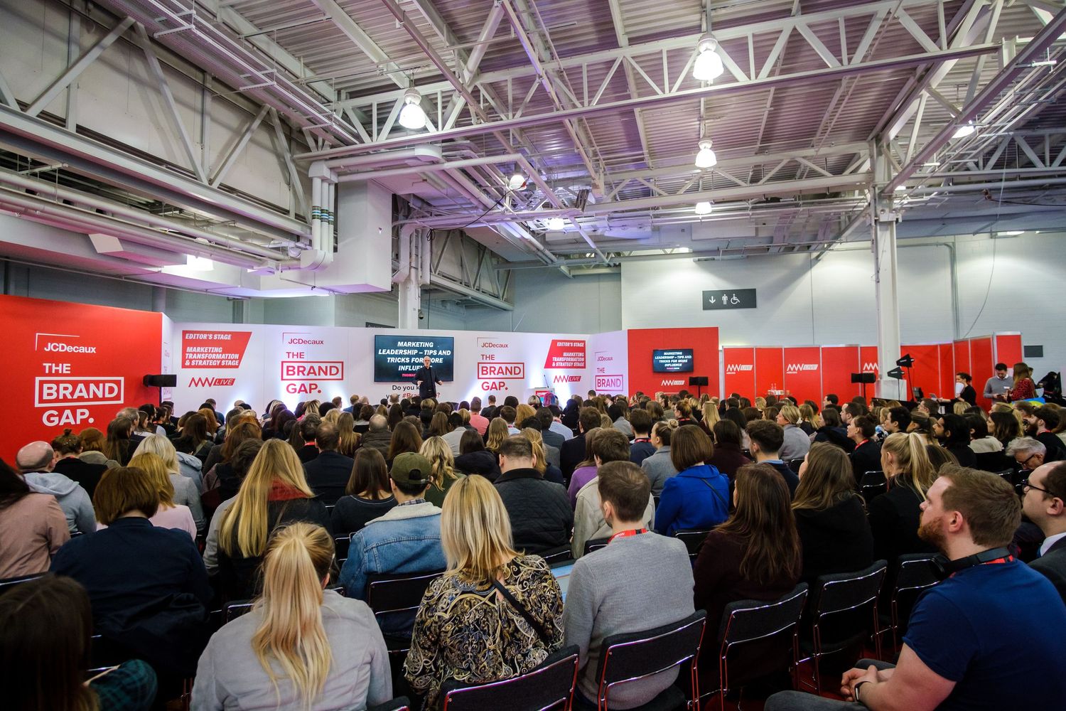 Large conference hall filled with attendees seated in rows during a business event.