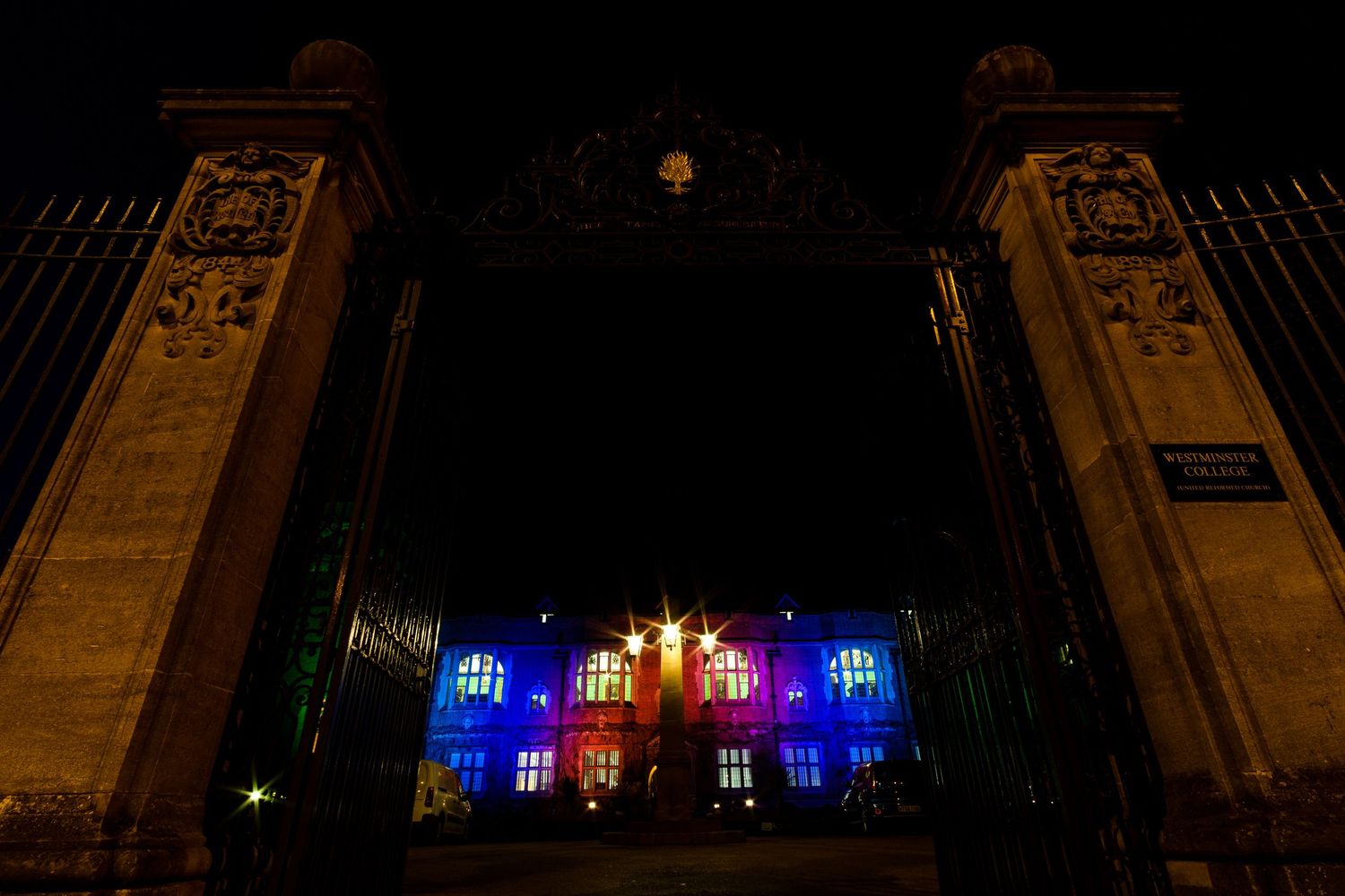 Historic building illuminated with colorful lights against dark night sky.