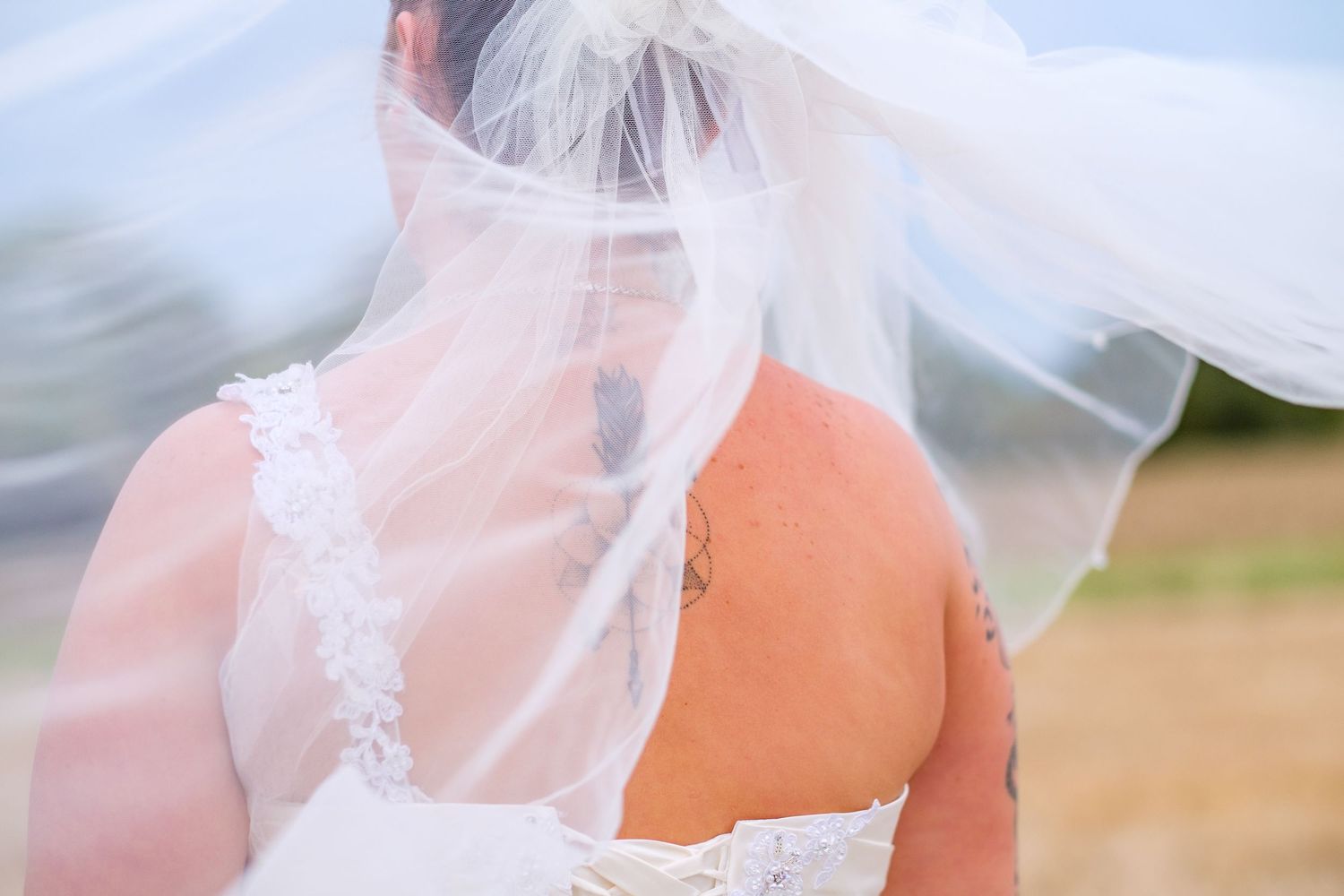 Close-up details of a white wedding dress with delicate lace and veil in natural lighting.