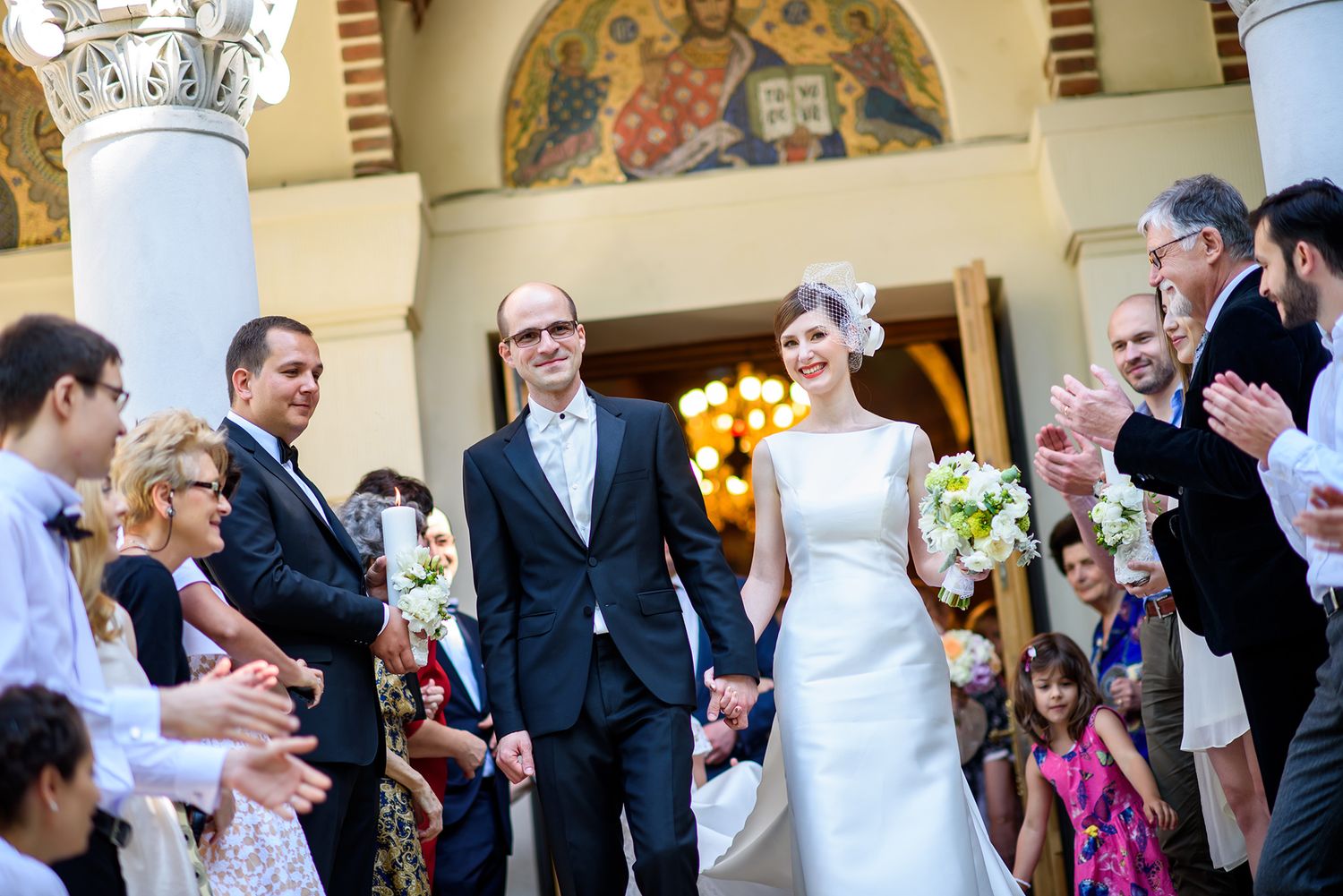 Wedding guests celebrate during an outdoor reception in front of an ornate building with classical architecture.
