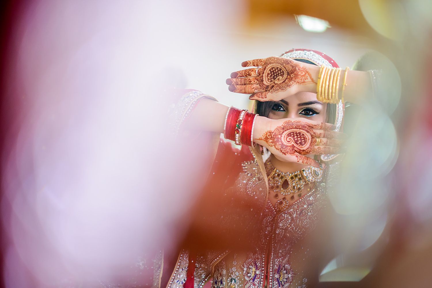 Ornate Rolls Royce hood emblem against a blurred background at a luxury Indian wedding ceremony.