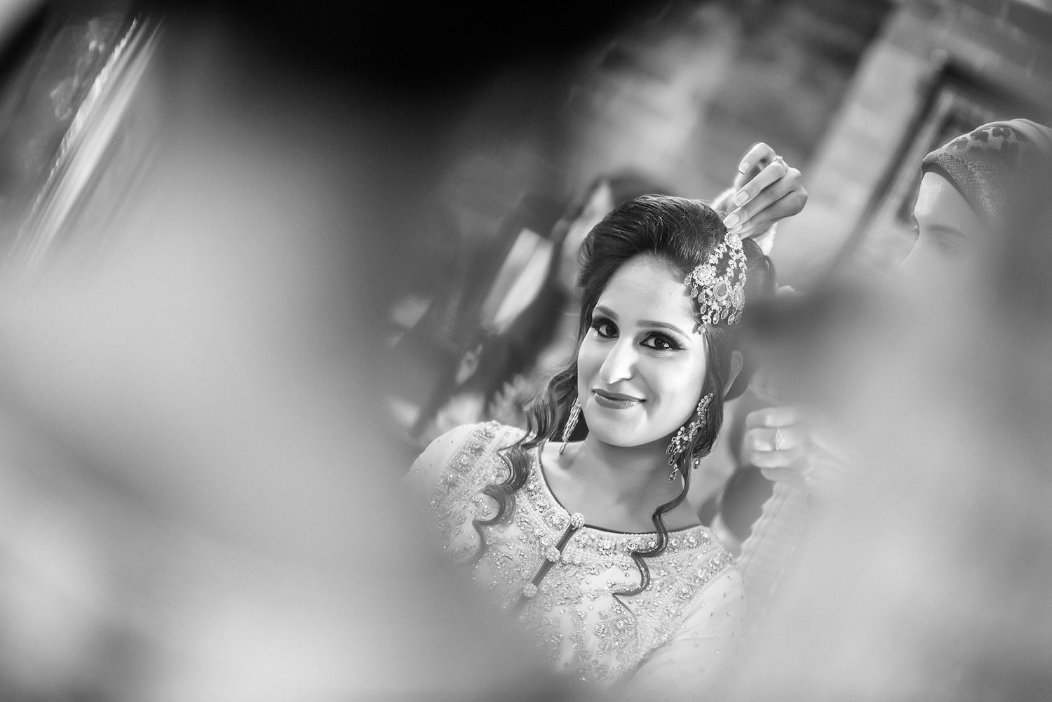A black and white artistic portrait showcasing traditional bridal jewelry and attire.
