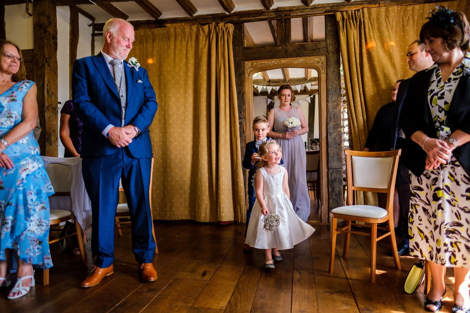 Wedding reception venue with gold curtains and wooden beams creating a warm atmosphere.