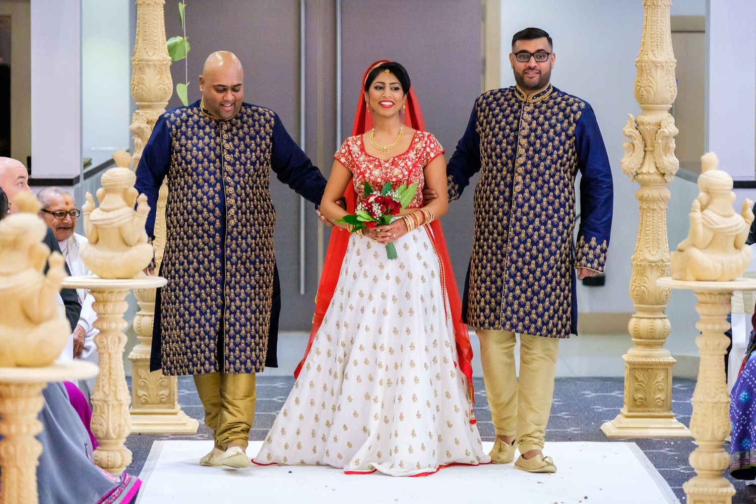 Festive wedding celebration in an elegant venue with ornate golden pillars and decorative details.