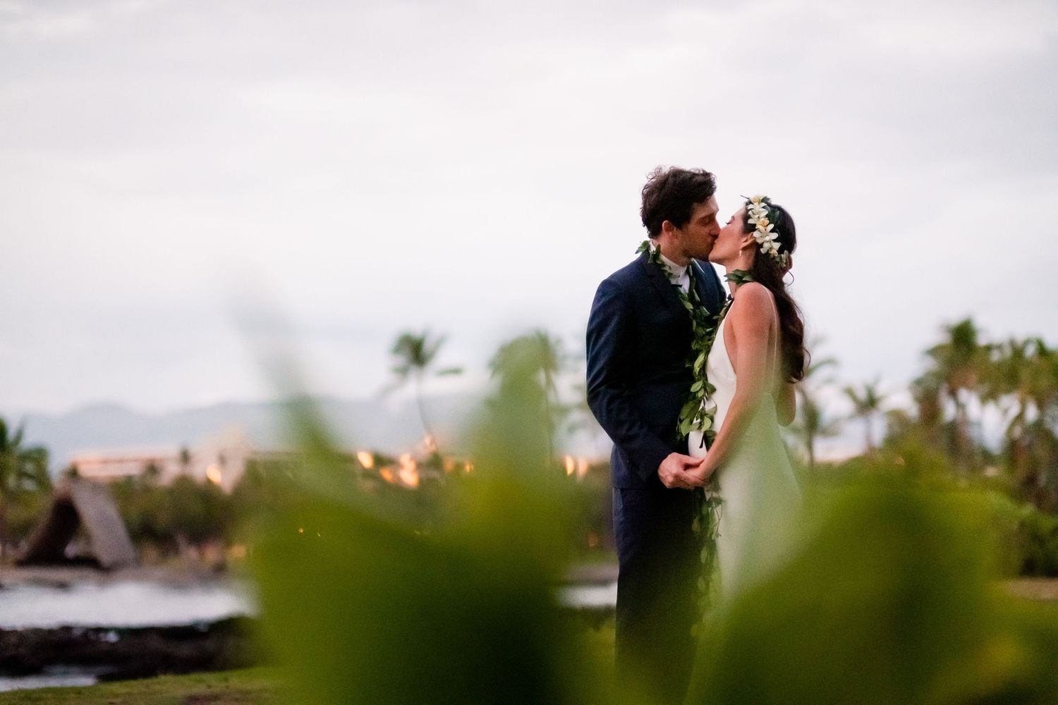 Couple shares an intimate moment during sunset at a beachside wedding celebration.
