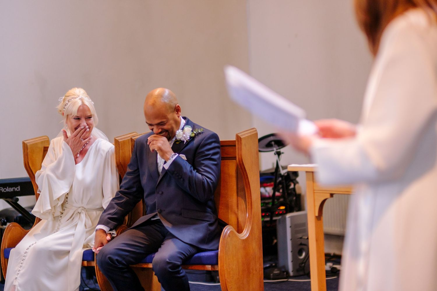 Emotional moment during a wedding ceremony as attendees sit in wooden church pews.