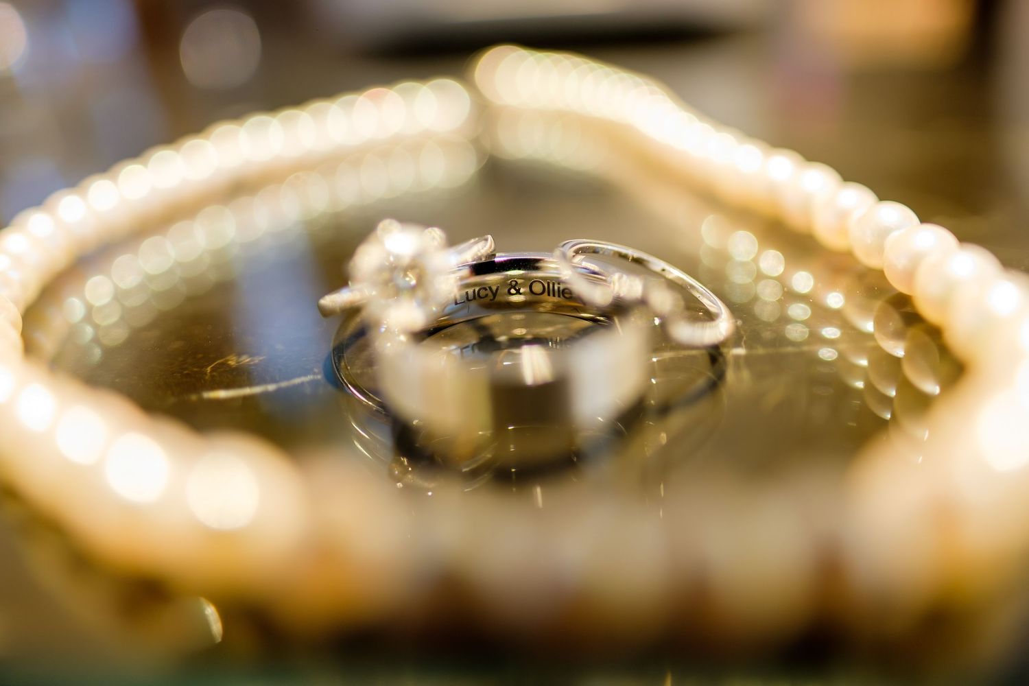 Macro shot of wedding rings with shallow depth of field creating a soft bokeh effect in golden light.