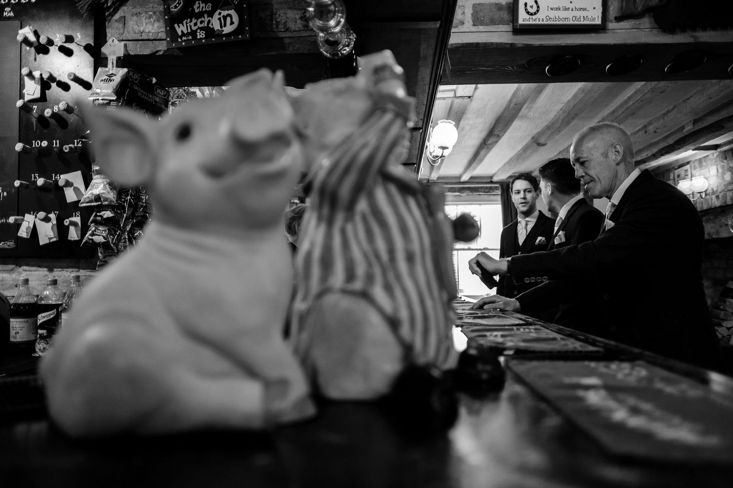 Wedding guests enjoying drinks and conversation at a rustic bar venue.