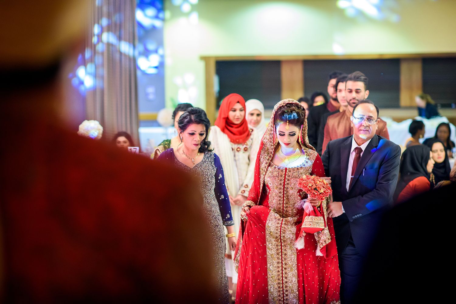 Guests gather at an elegant indoor celebration wearing traditional formal attire.