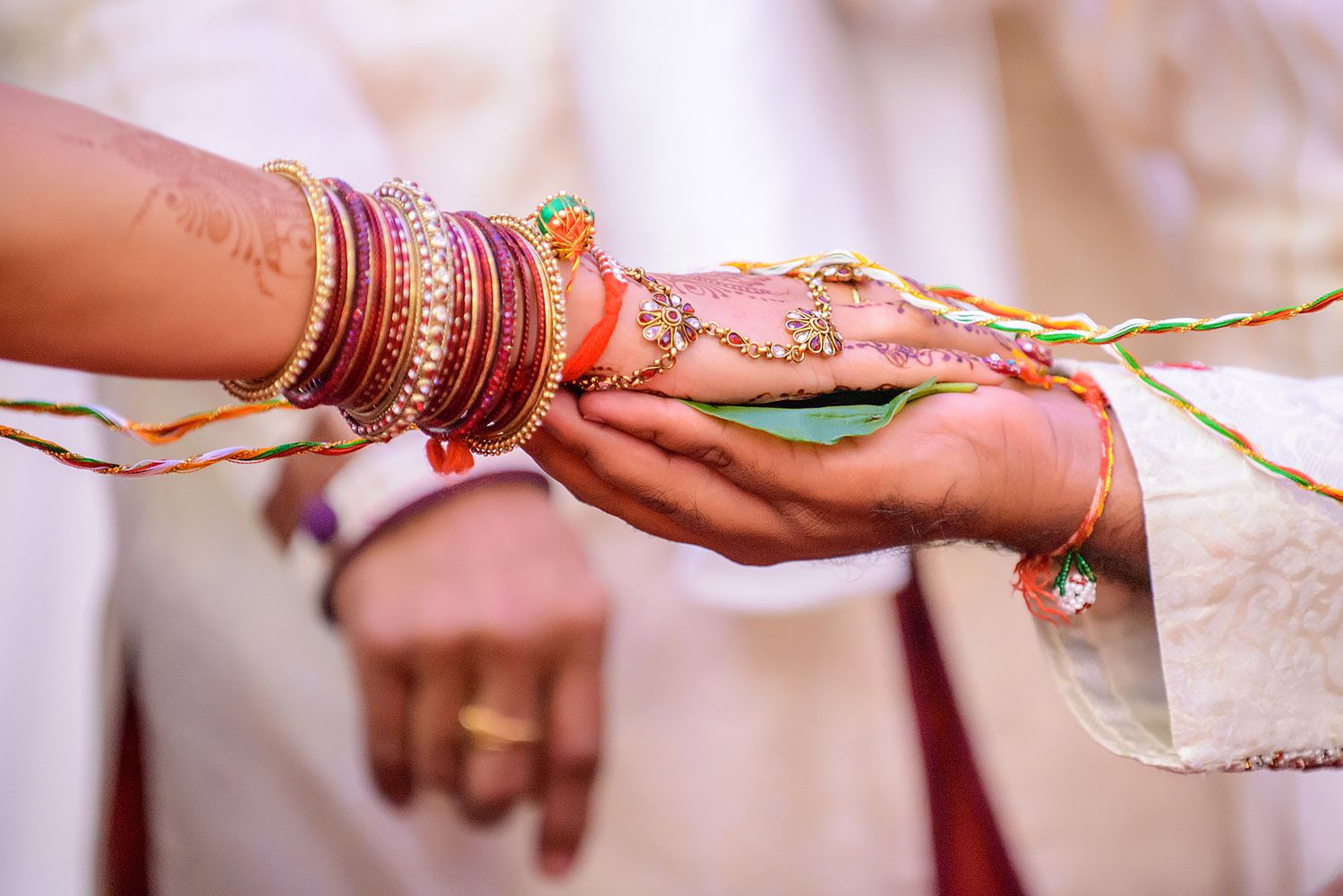Close-up shots of hands with traditional Indian wedding bangles and jewelry during ceremony rituals.