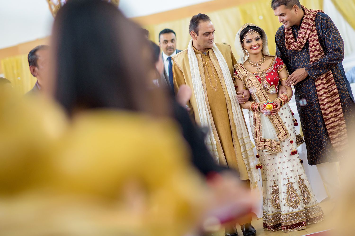 Wedding guests enjoying festivities in a brightly lit celebration hall.