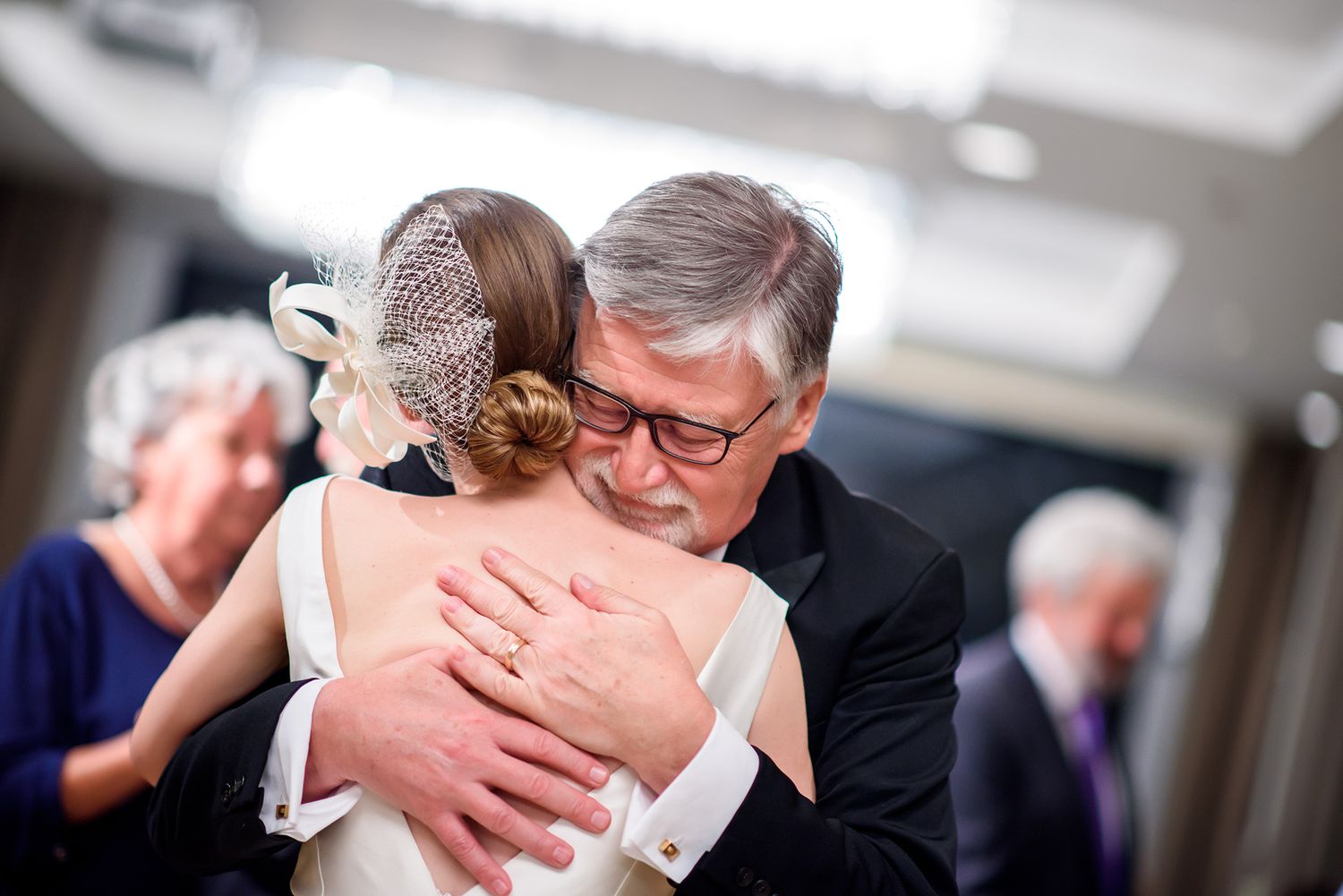 Candid moments of dancing and embracing at an elegant indoor wedding celebration.