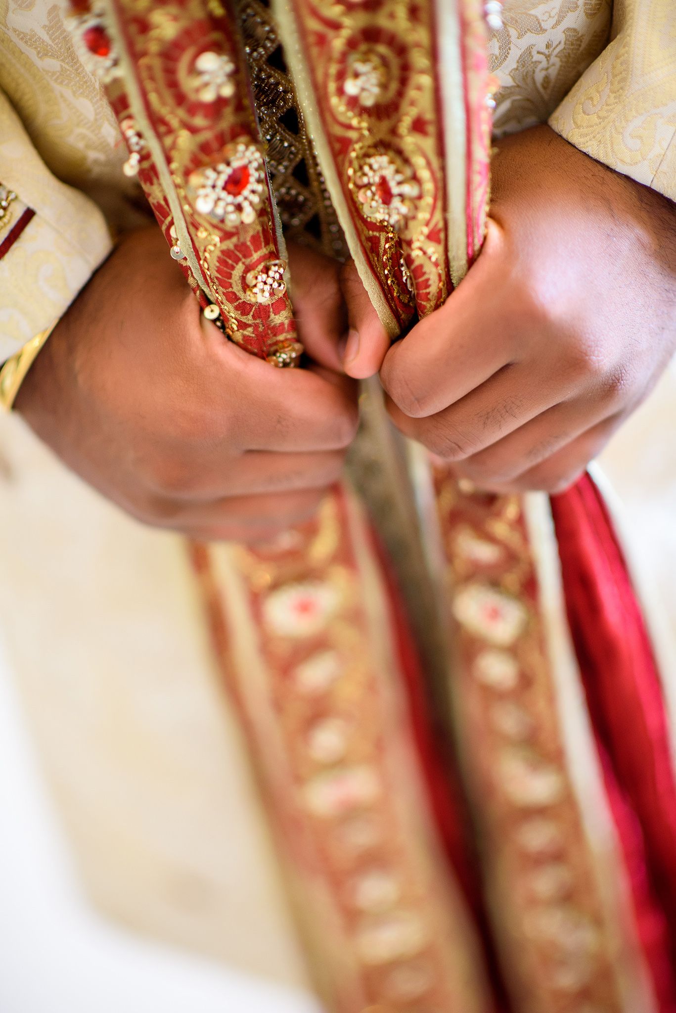 Close-up detail of intricate red and gold embroidery on traditional Indian wedding attire.