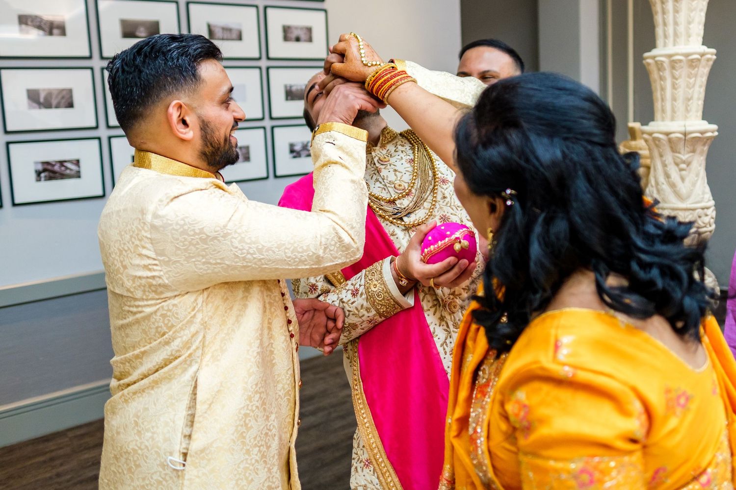 Wedding ceremony participants perform traditional rituals in formal Indian attire.