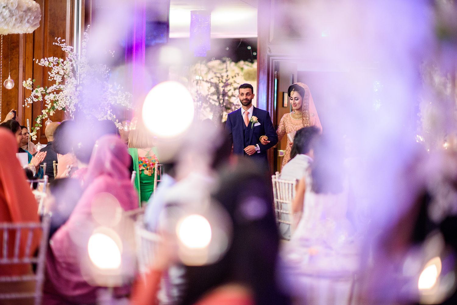 Dreamy wedding reception scene with purple lighting and bokeh effects.