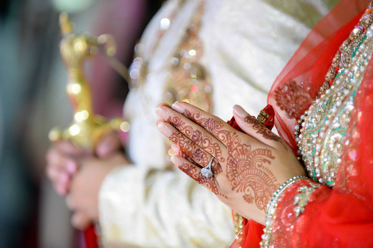 Close-up of intricate henna design on hands with traditional Indian wedding attire.
