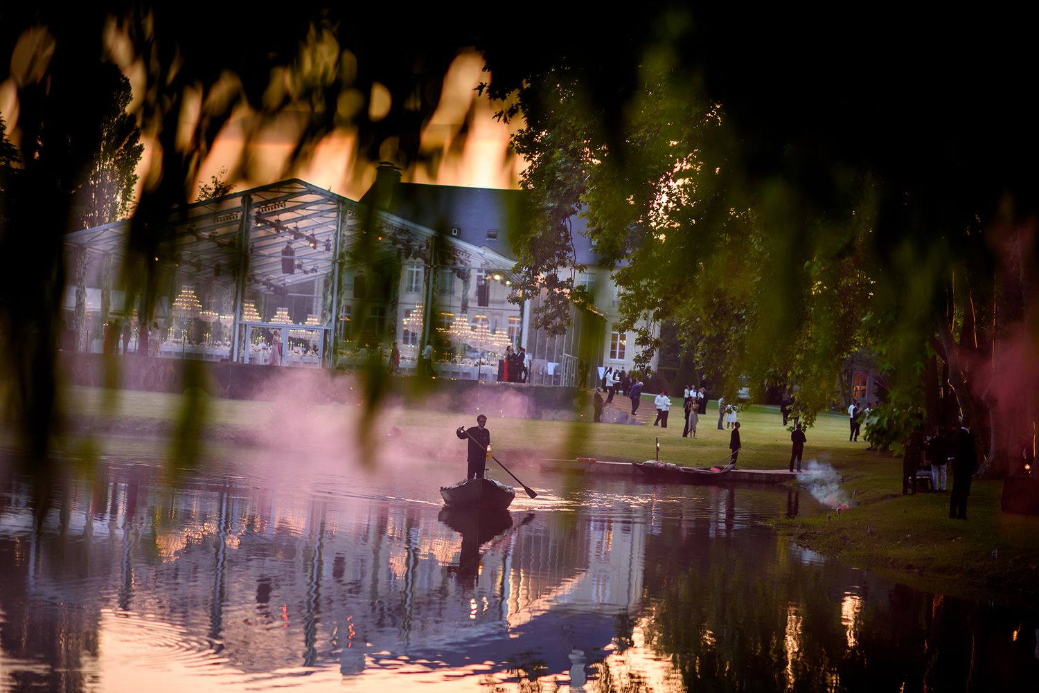 Evening wedding reception by a reflective lake with ambient lighting creating a romantic atmosphere.