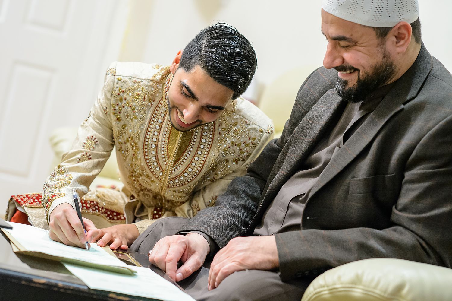 Traditional Muslim wedding ceremony signing with documents on table.