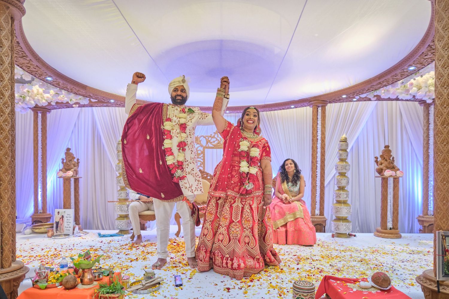 Elegant Indian wedding ceremony setup with traditional red and gold decor in a luxurious ballroom.