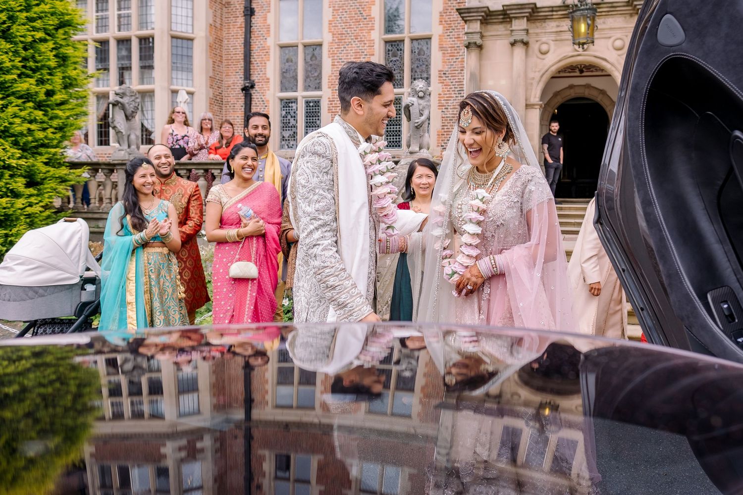 Elegant outdoor wedding ceremony with guests in colorful attire gathered around a reflective surface.