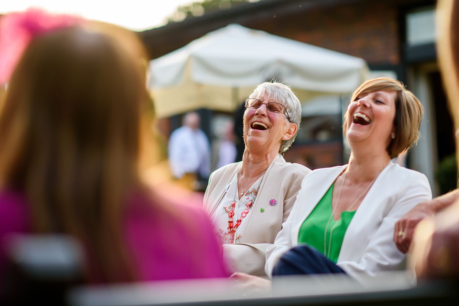 Guests share joyful laughter during outdoor wedding festivities.