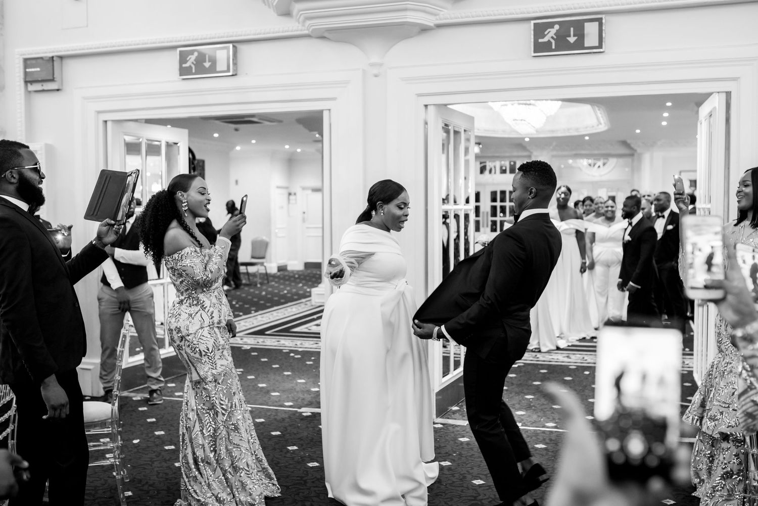 Wedding party guests dance and celebrate on the dancefloor at an elegant indoor reception venue.