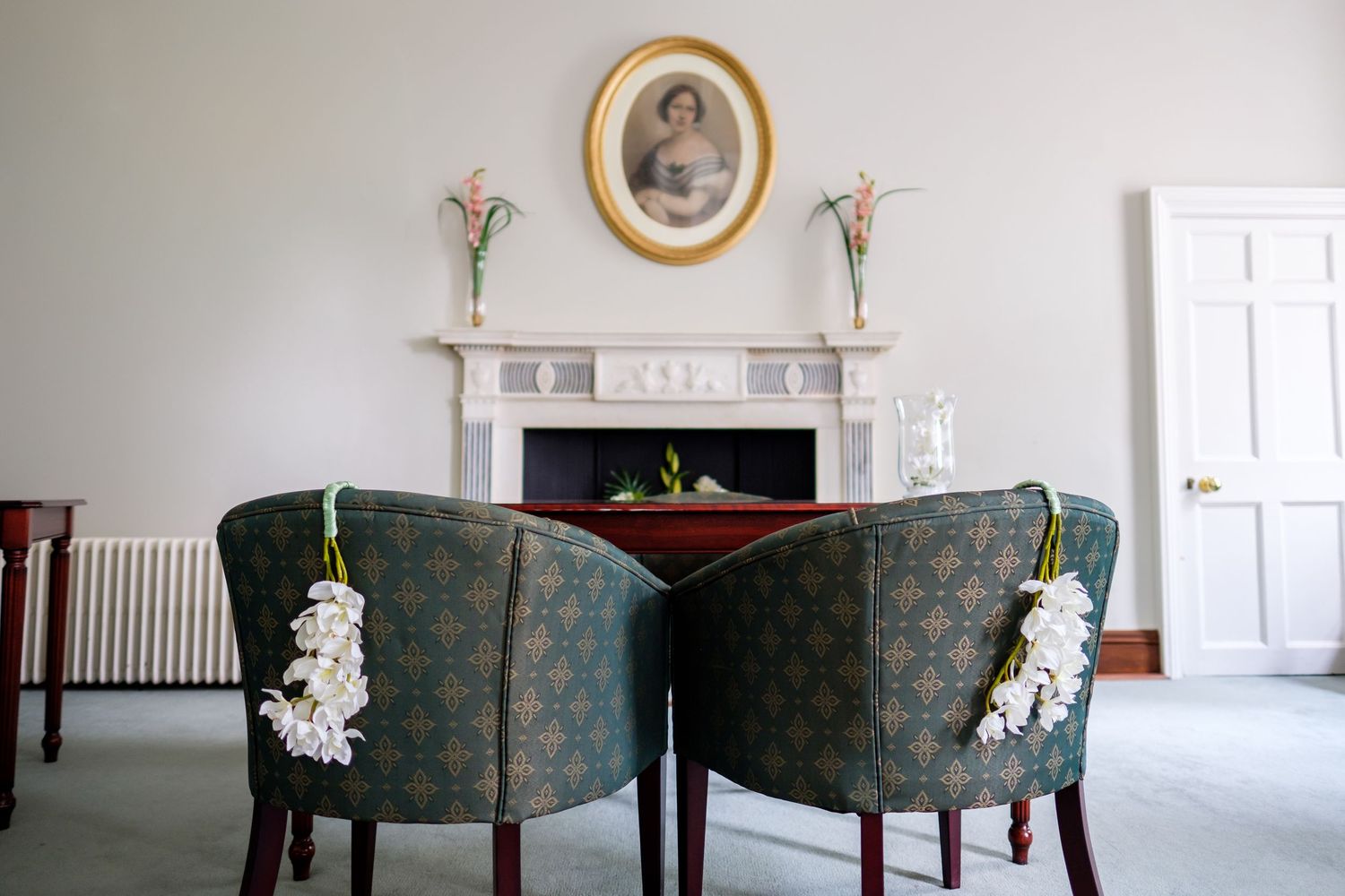 Minimalist room interior with vintage frames and green upholstered chairs.