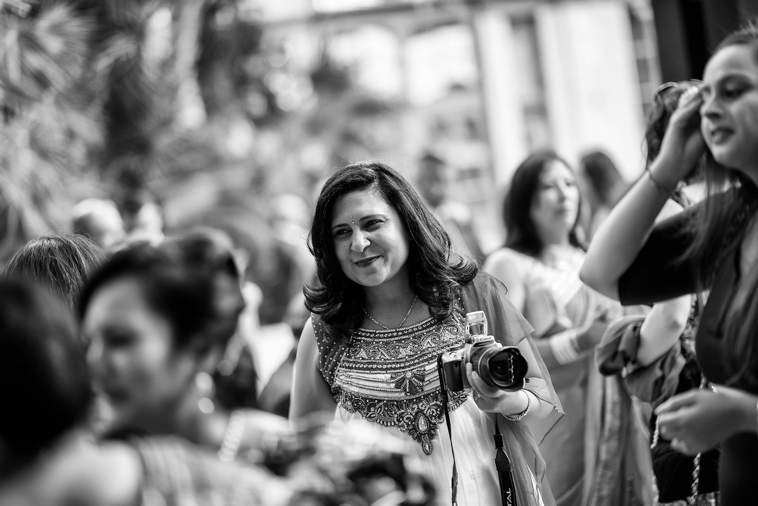Candid black and white photo of guests enjoying celebration at outdoor event.