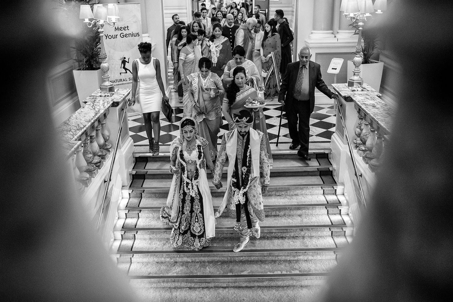 Black and white photo of wedding guests gathered on grand staircase.