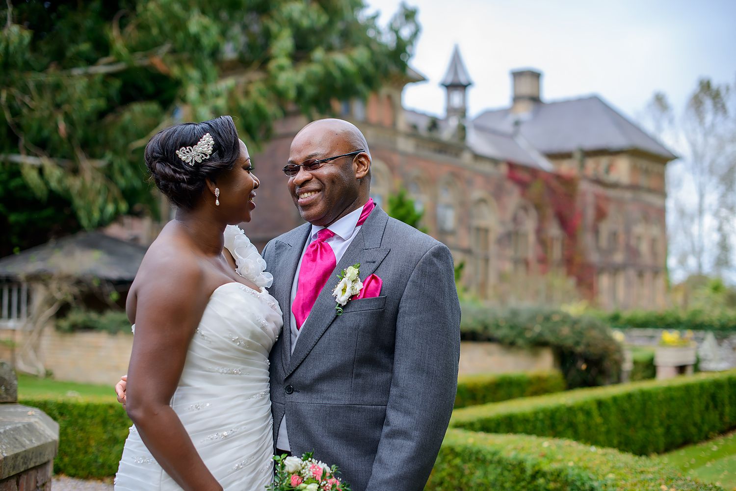 Wedding couple shares romantic moments in front of historic stone building.