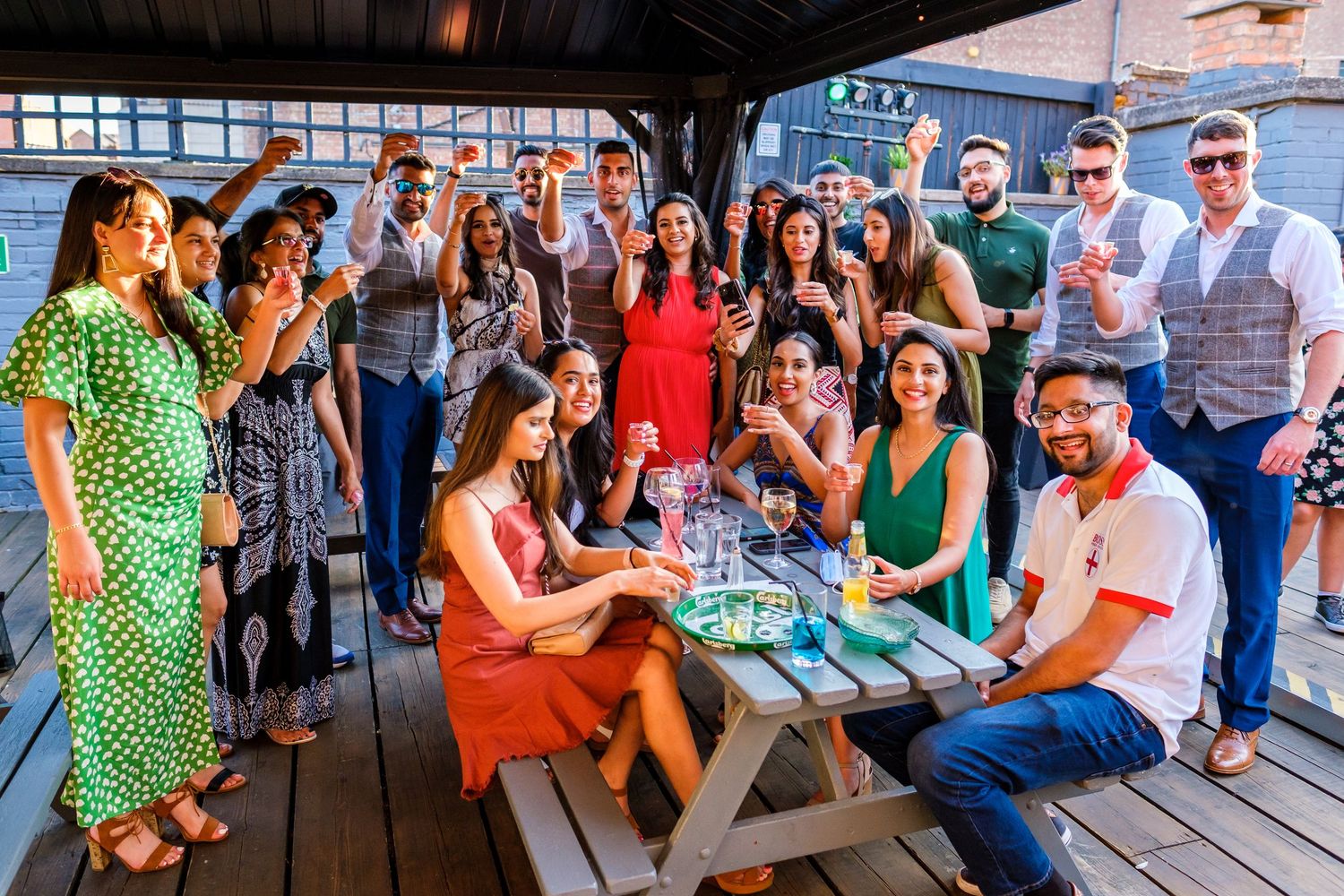 A group of people enjoying drinks and conversation on an outdoor patio during a social gathering.