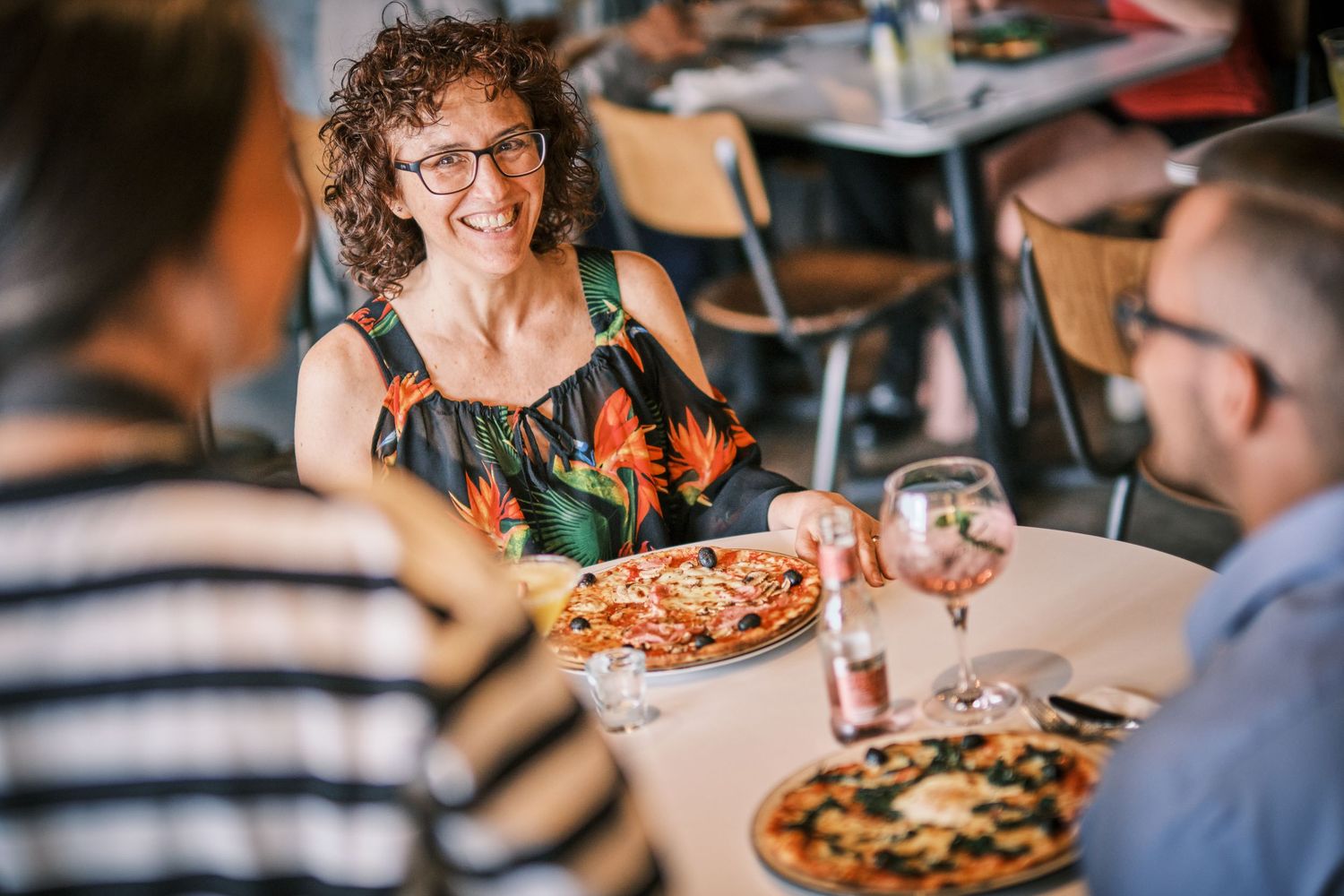 Restaurant dining scene with pizzas being served on wooden tables.