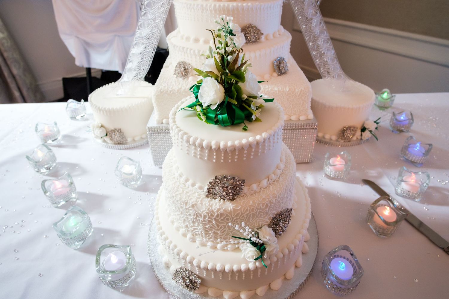 Elegant three-tiered white wedding cake with delicate piping details and butterfly decorations on display at reception.