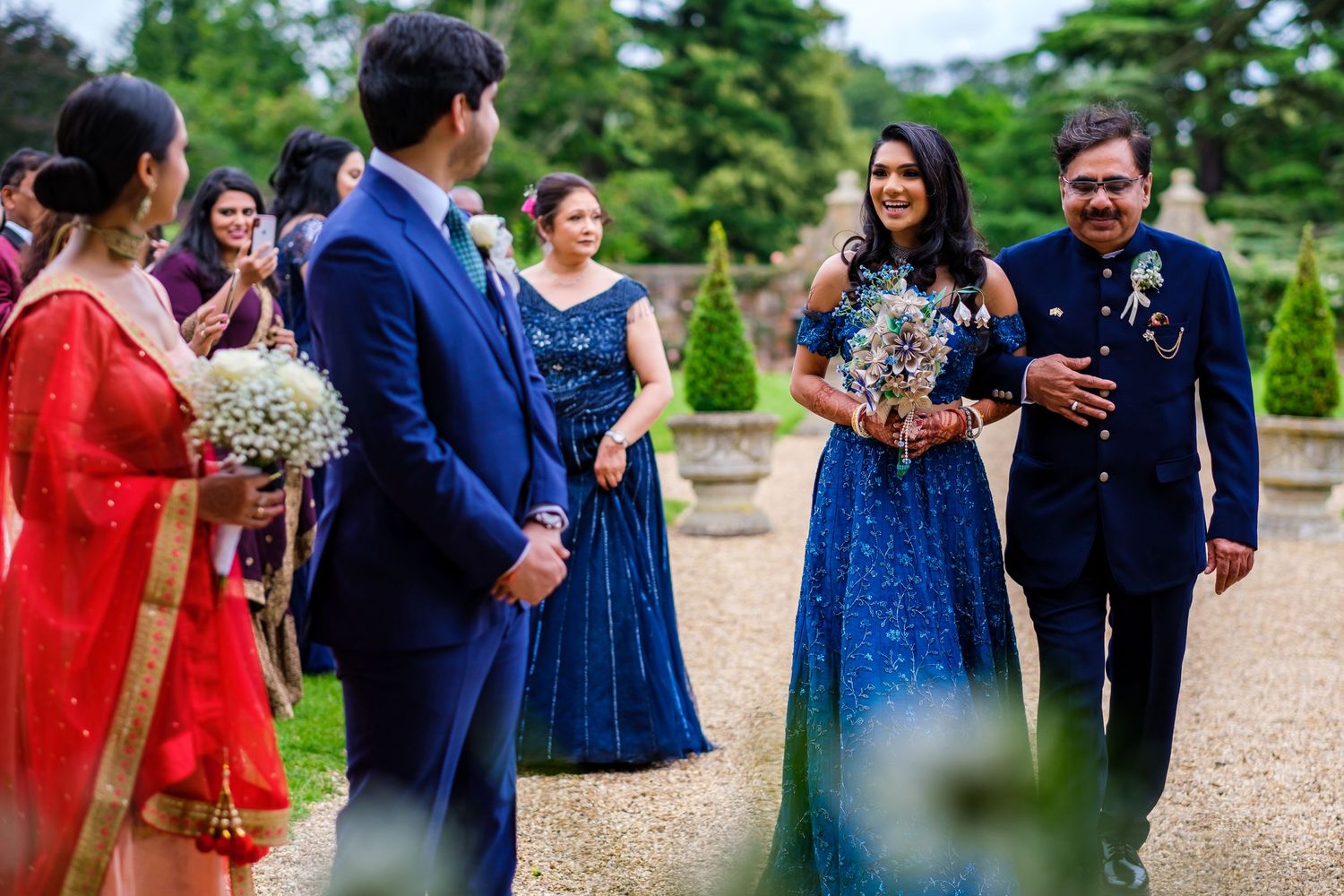 Wedding guests in colorful attire enjoying a festive outdoor celebration with white chairs.