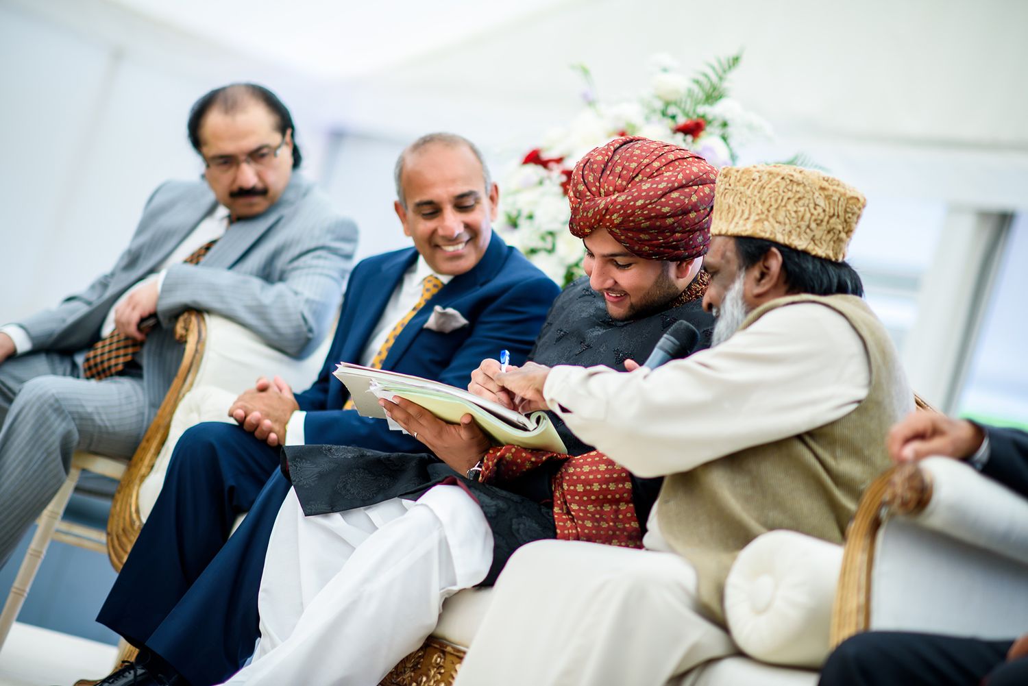 Indoor wedding celebration with traditional cultural elements and formal attire.