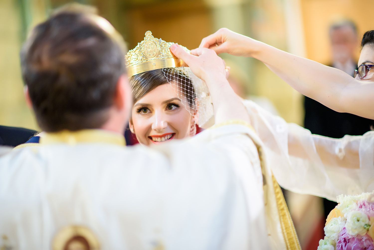 Joyful wedding celebration with guests in formal attire under warm lighting.