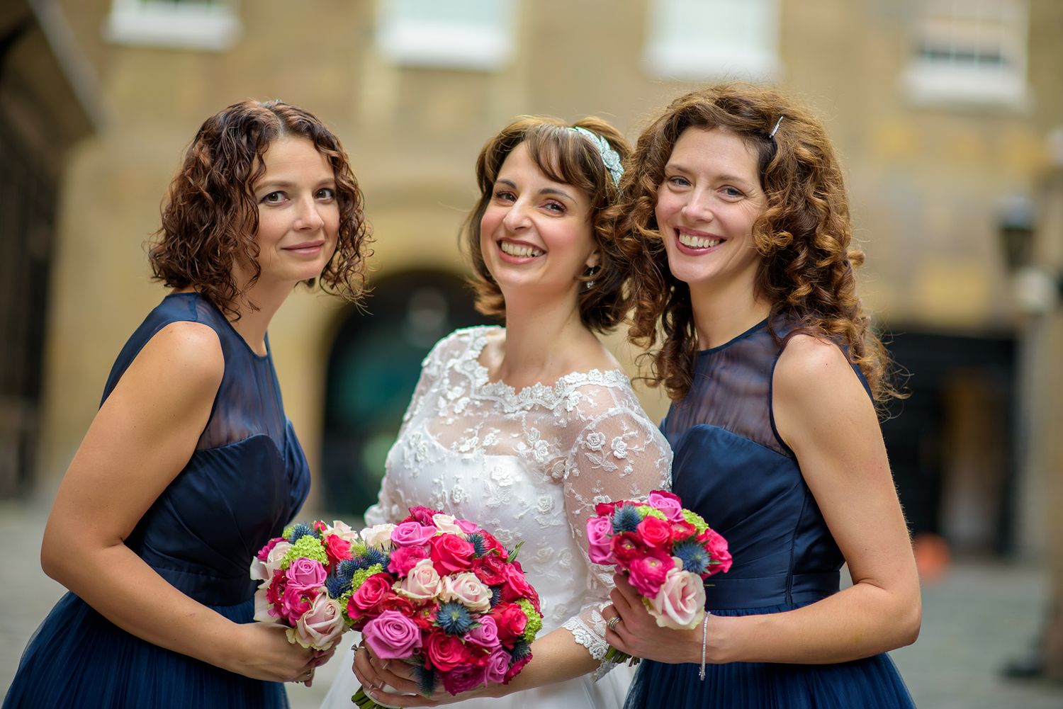 Bridesmaids in navy blue dresses share joyful moment outdoors.
