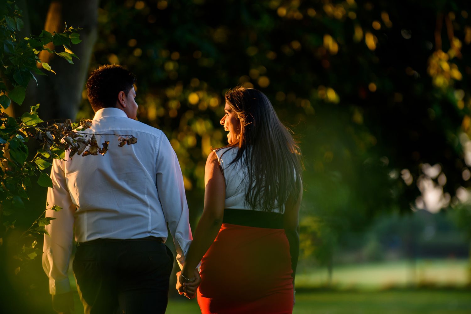 A couple walking through a sunlit park during golden hour.