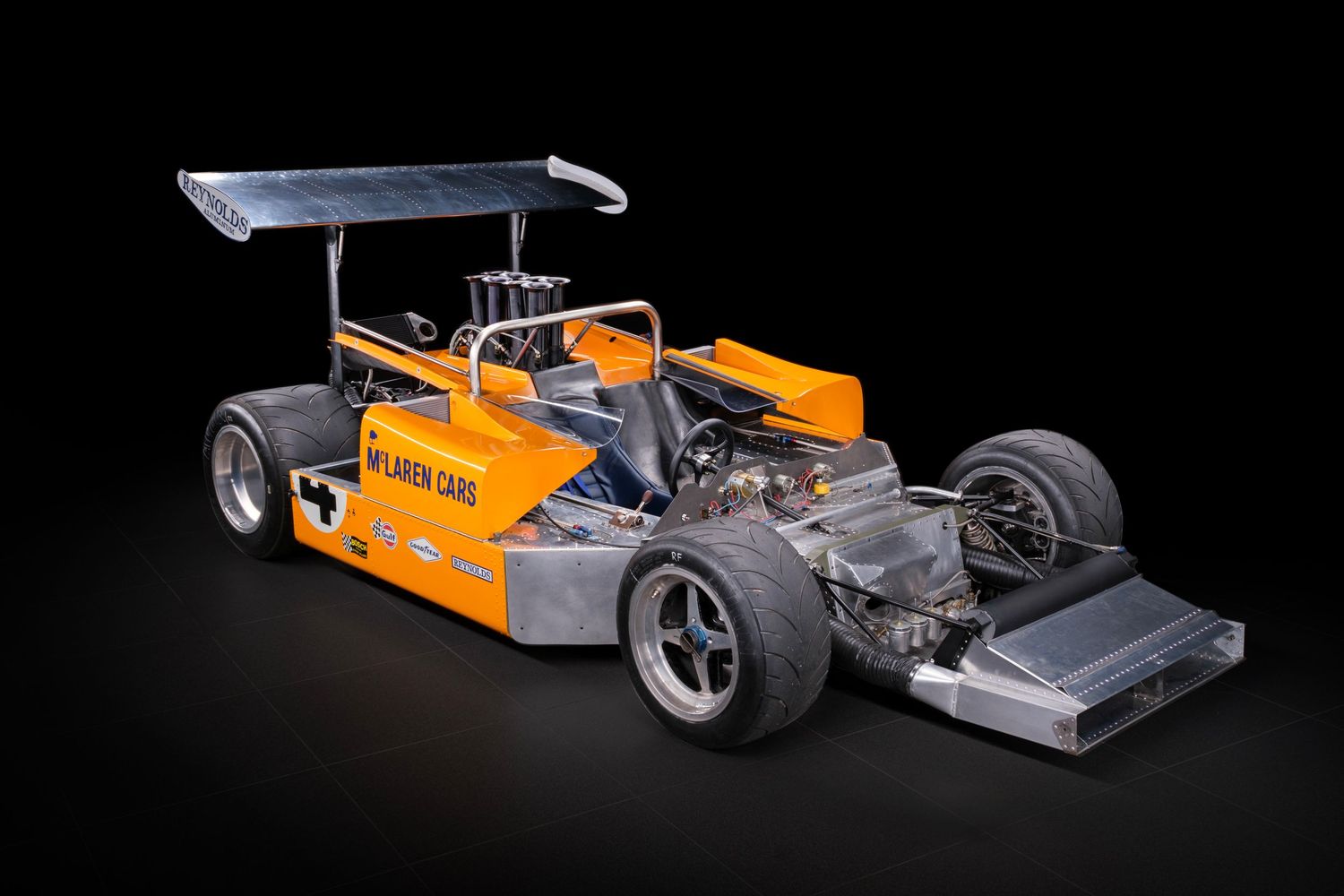 Series of orange and gray Formula 1 race cars displayed on black background showcasing aerodynamic design.